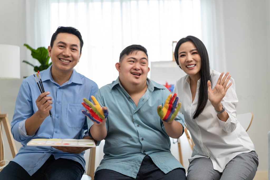 Asian happy family draw picture with down syndrome son in living room.