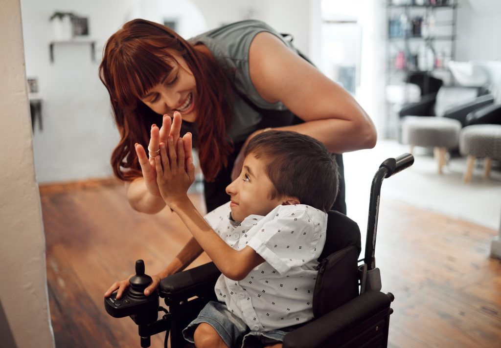 Hairdresser, high five and child in hair salon happy with hair cut or hairstyle. Disabled kid in wh